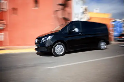 Mercedes Clase V negro circulando por una calle de fachadas de colores
